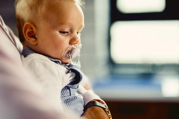 a baby's pacifier with a hand gently removing it, representing tips and tricks for parents to stop pacifier use.