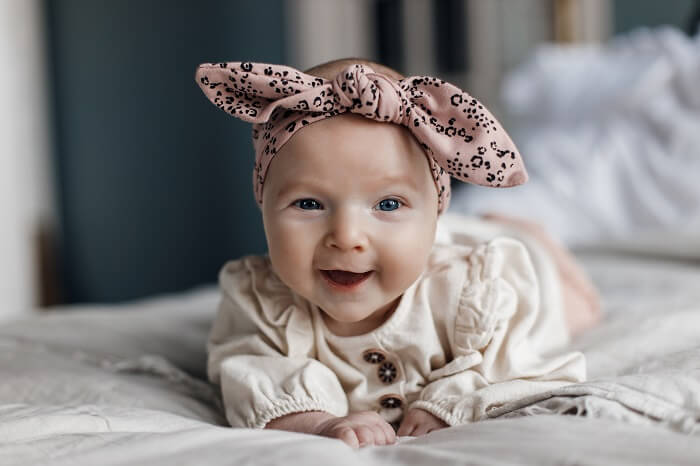 A photo of a smiling baby wearing a colorful onesie and a matching hat