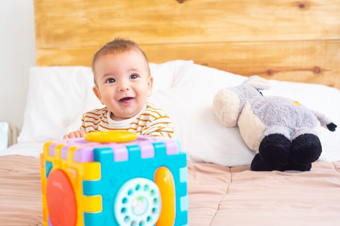 A 9-month-old baby sitting on a mat, surrounded by textured objects, engaging in sensory exploration and play