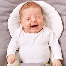 Close-up photo of a newborn baby crying, expressing distress and confusion