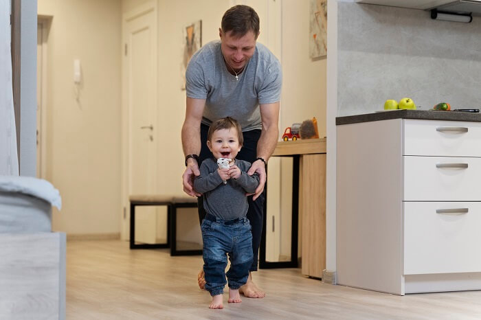 Father helping his toddler take their first steps