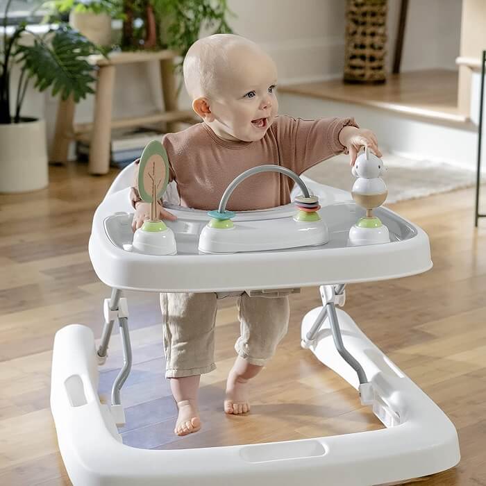 Image a baby walker placed in a safe and spacious environment, away from hazards, with toys and play mats for the baby's enjoyment and under the watchful eye of a caregiver.