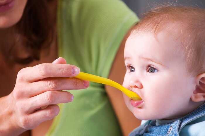 Parent feeding baby a spoonful of pureed food