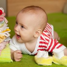 A smiling newborn baby wearing an all-in-one cloth diaper, surrounded by a cozy nursery setting.