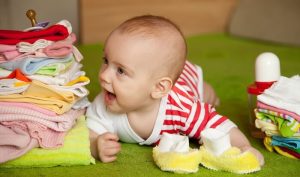 A smiling newborn baby wearing an all-in-one cloth diaper, surrounded by a cozy nursery setting.