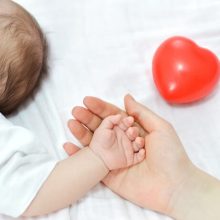 Caring hands holding a newborn baby - Dealing with common newborn ailments