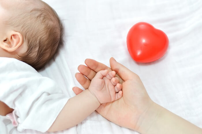 Caring hands holding a newborn baby - Dealing with common newborn ailments