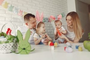 Image of toddlers celebrating Easter with colorful activities such as egg painting, egg hunting, bunny hop races, and crafts. The scene depicts a lively and joyful Easter Eggstravaganza for little hands.