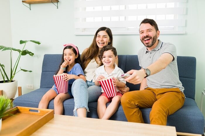 Parents and kids enjoying a movie night together on the couch.