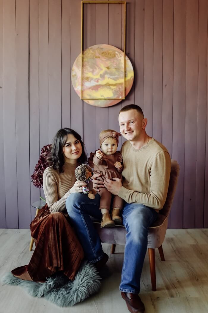 A loving family embraces their newborn baby in a beautifully decorated nursery while a professional photographer captures the heartwarming moment. Soft, natural light fills the room, creating a warm and inviting atmosphere.